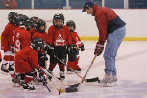 Children learning hockey from coach